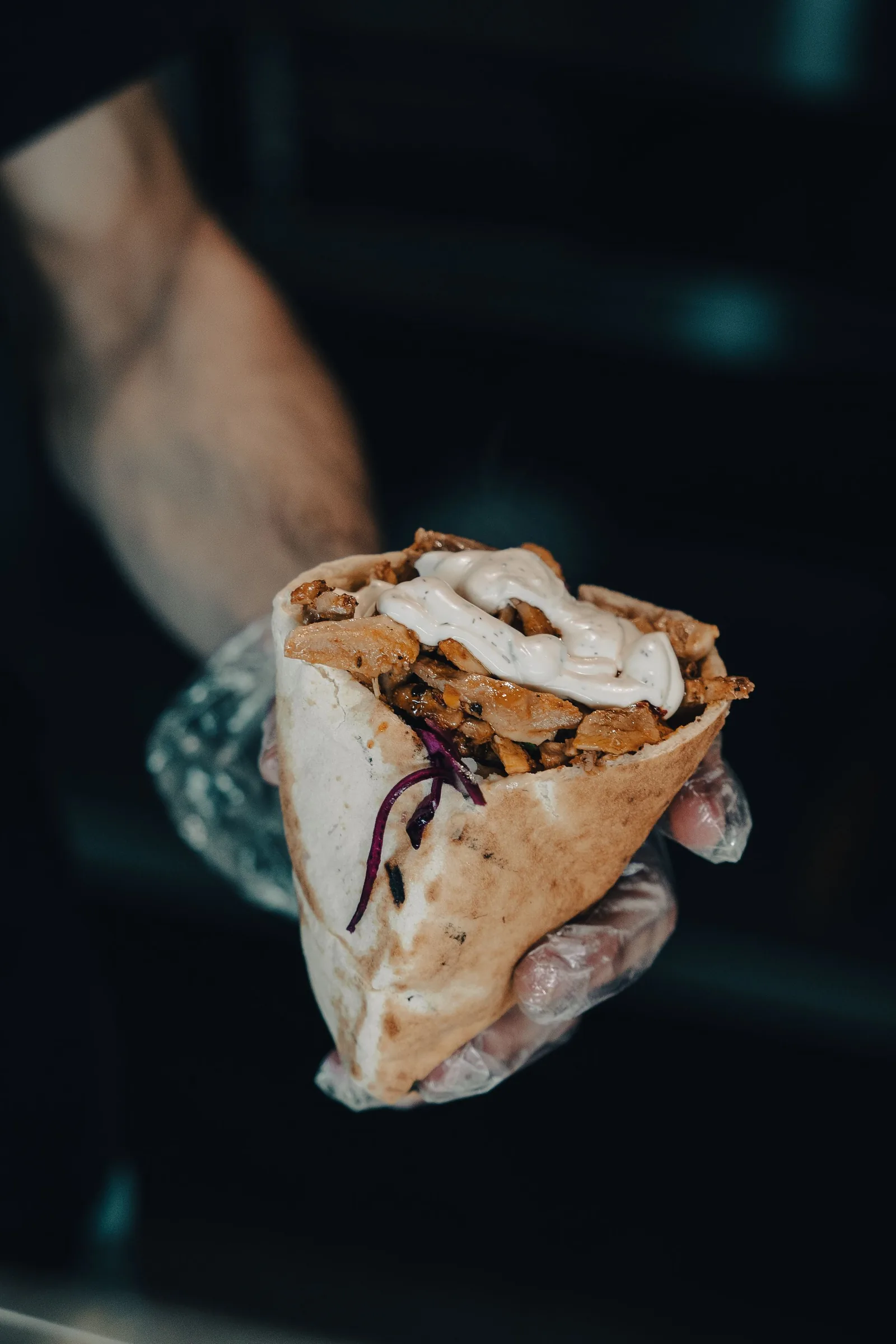 A freshly rolled shawarma handed over in a gloved hand